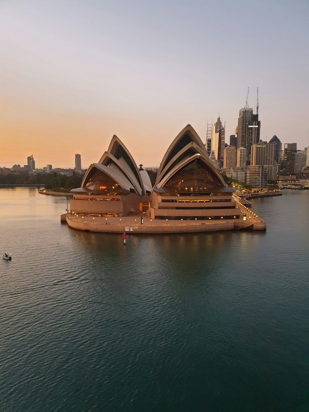 The Sydney Opera House and the city skyline across the harbour at golden hour